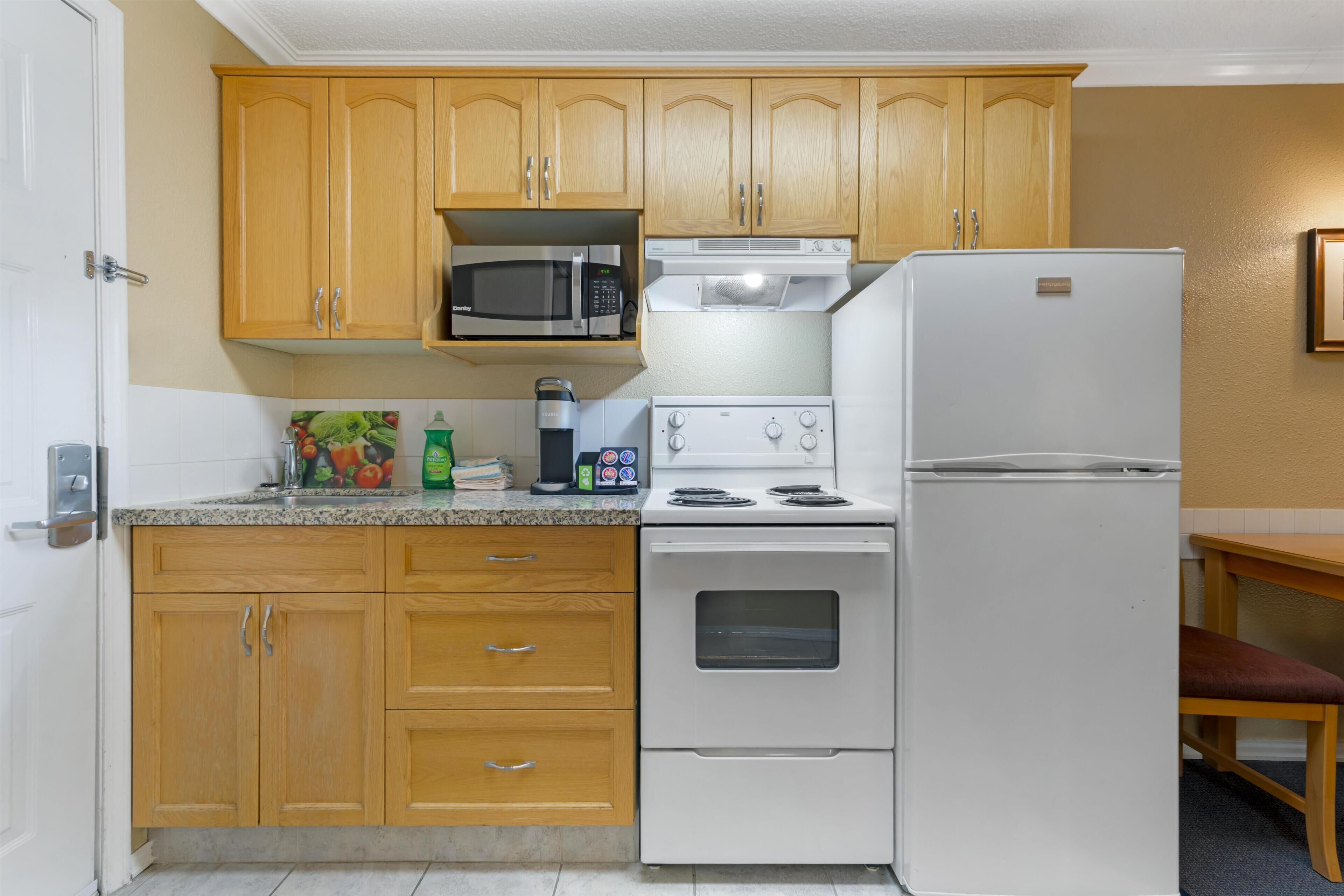 A kitchen with wooden cabinets, a microwave, a stove, and a refrigerator.