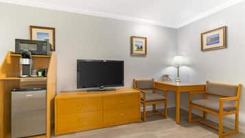 Una habitación compacta con televisión de pantalla plana, muebles de madera, refrigerador y cuadros en las paredes.