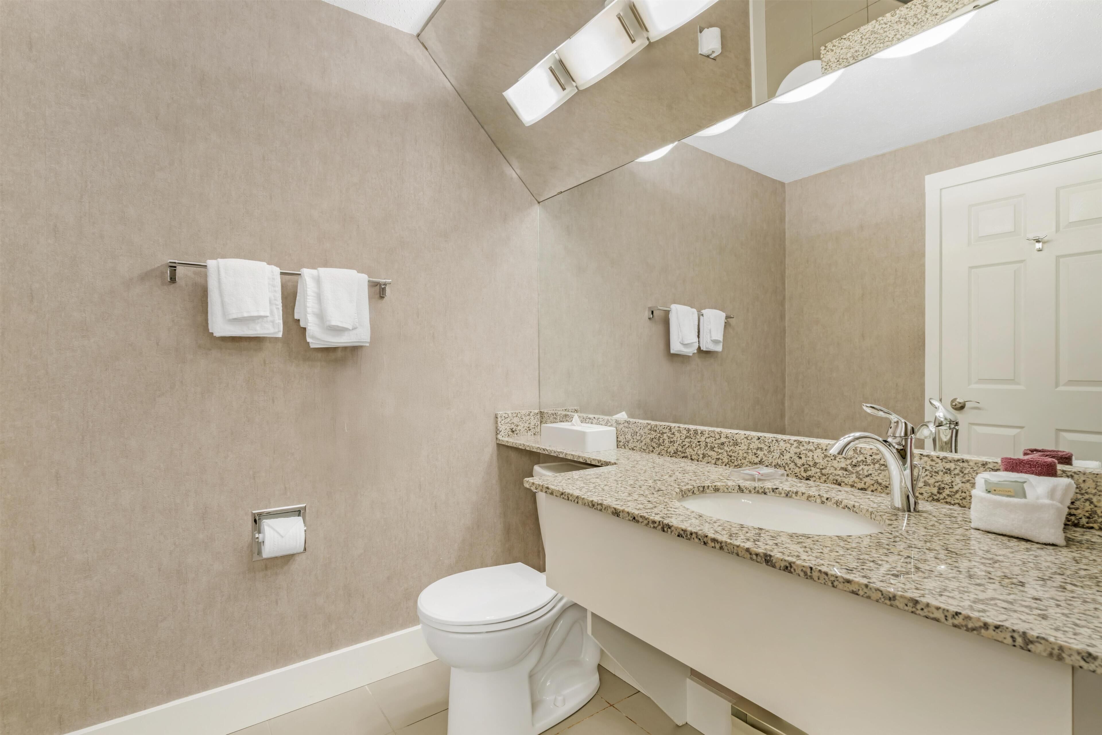 Un baño moderno con inodoro, lavamanos y perchero para toallas.