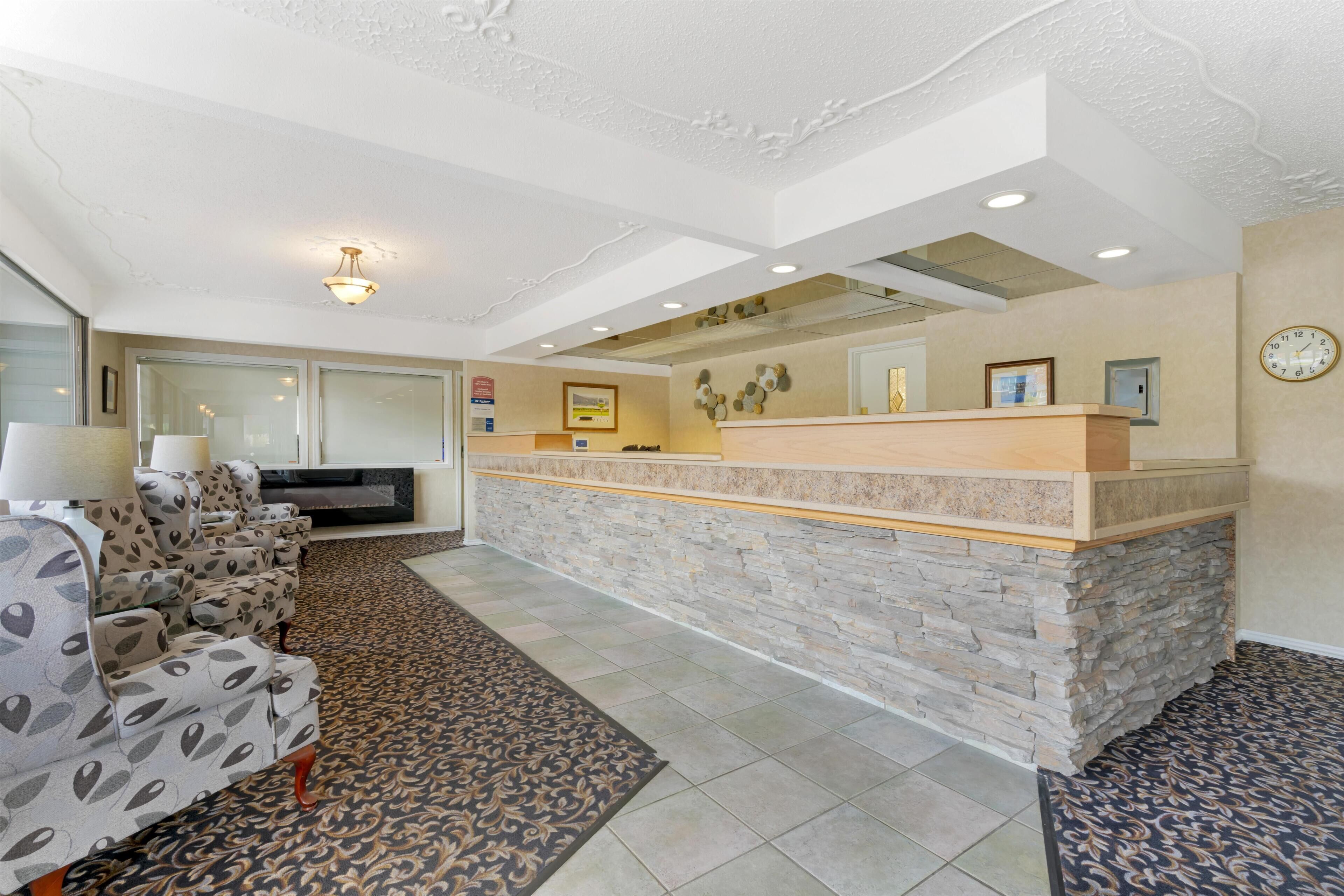 A reception area with a stone counter, patterned sofas, and a clock on the wall.