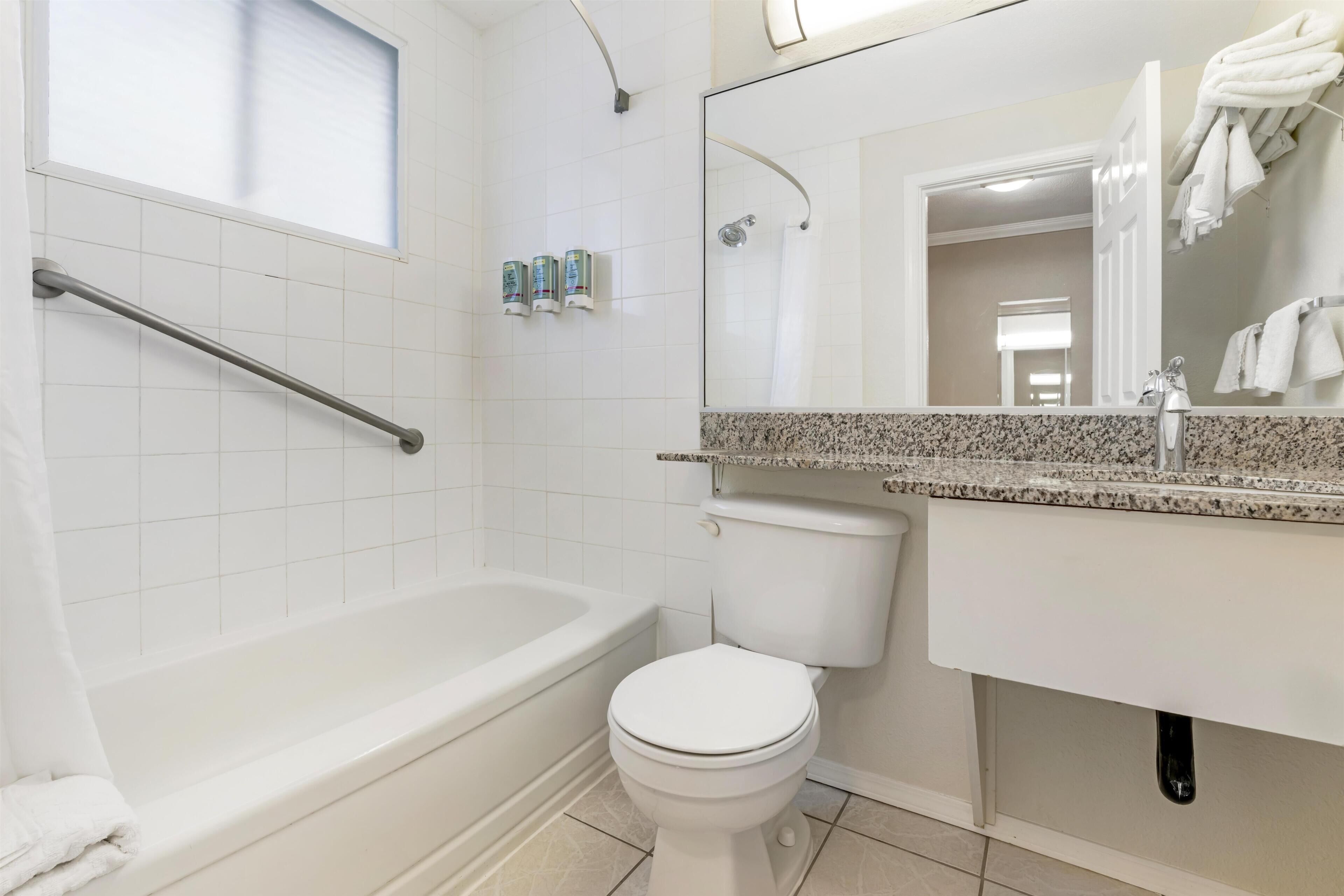 Un baño con bañera, inodoro y lavamanos con espejo.