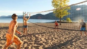 Ein Beachvolleyballspiel mit Netz und Spielern im Sand.