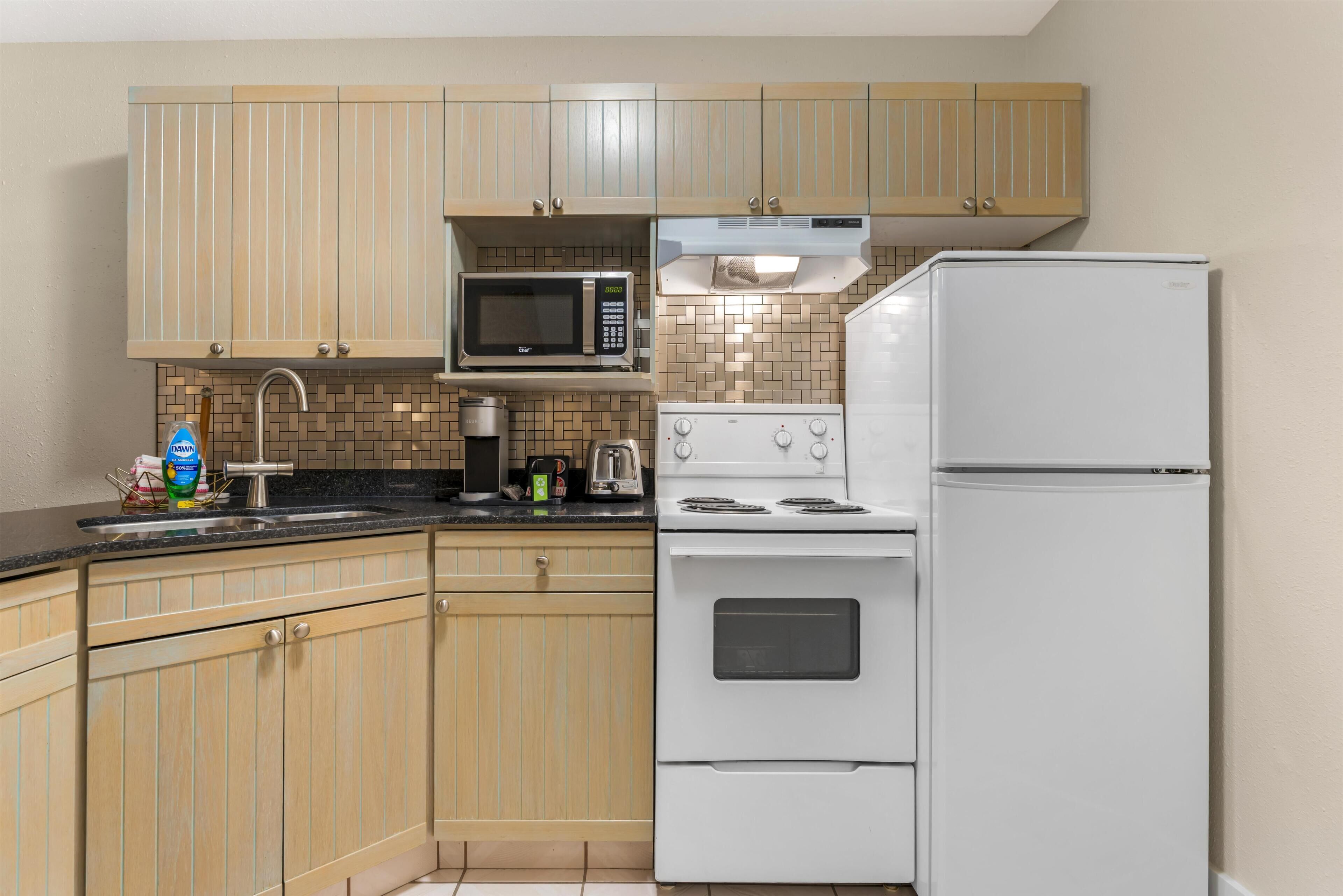 Una cocina con armarios de madera, microondas, estufa y refrigerador.