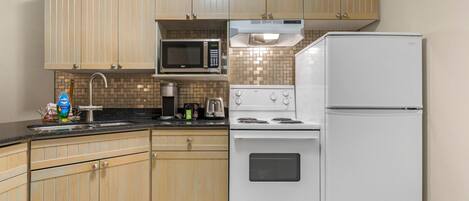 Una cocina con armarios de madera, microondas, estufa y refrigerador.