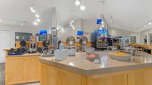 Ein Frühstücksbuffet mit einer Kaffeemaschine, einem Waffeleisen und verschiedenen Speisen.