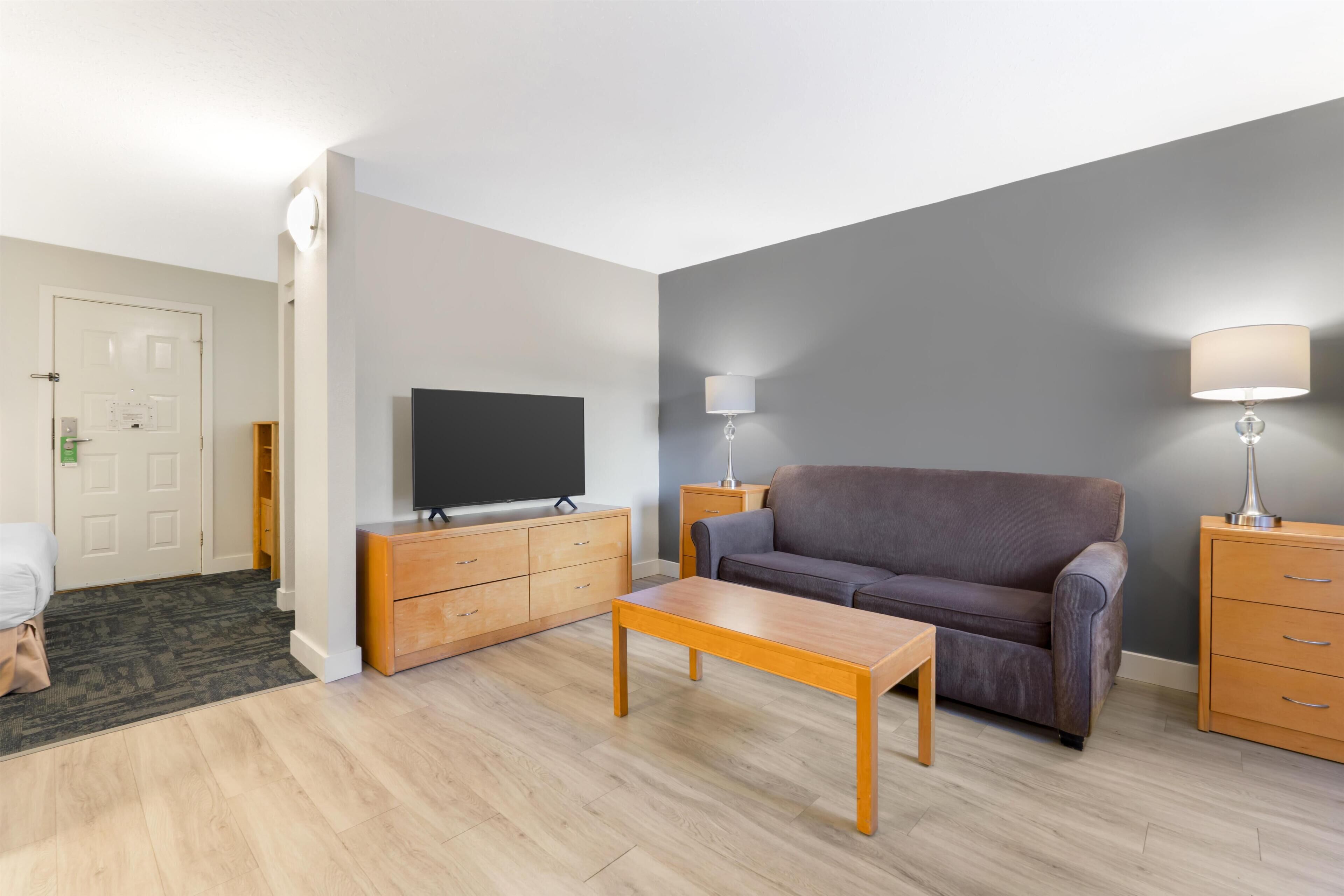 A living room with a sofa, a TV, a wooden coffee table, and a lamp.
