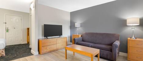 A living room with a sofa, a TV, a wooden coffee table, and a lamp.