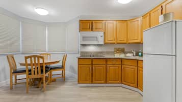 A kitchen with wooden cabinets, a microwave, a refrigerator, and a dining table with chairs.