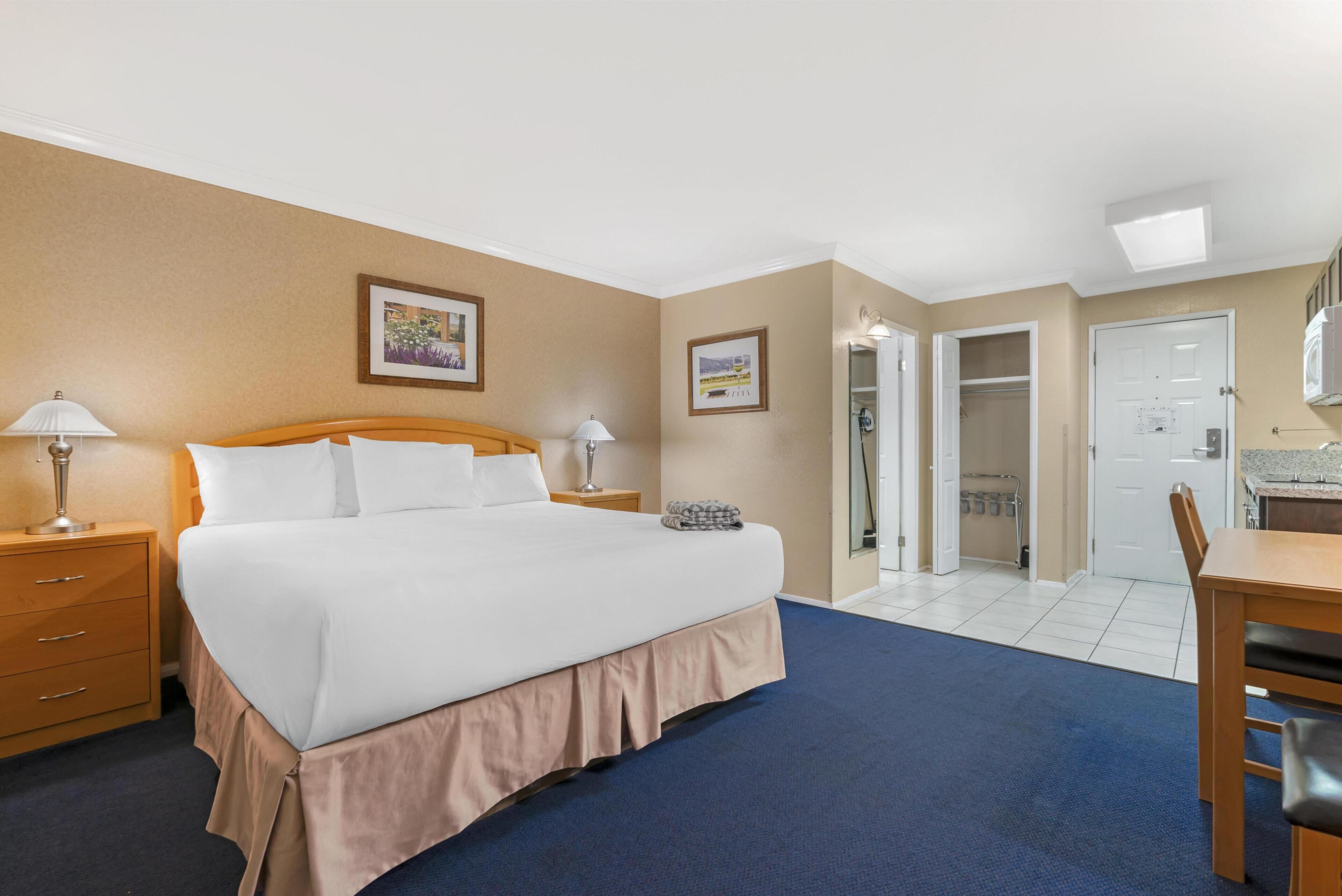 Une chambre d’hôtel comprenant un lit, des tables de chevet, un bureau et une armoire.