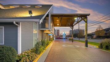 A hotel entrance with a covered walkway, a 'Lobby' sign, and a 'Best Western' sign in the distance.