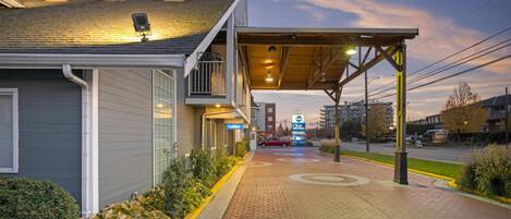 A hotel entrance with a covered walkway, a 'Lobby' sign, and a 'Best Western' sign in the distance.