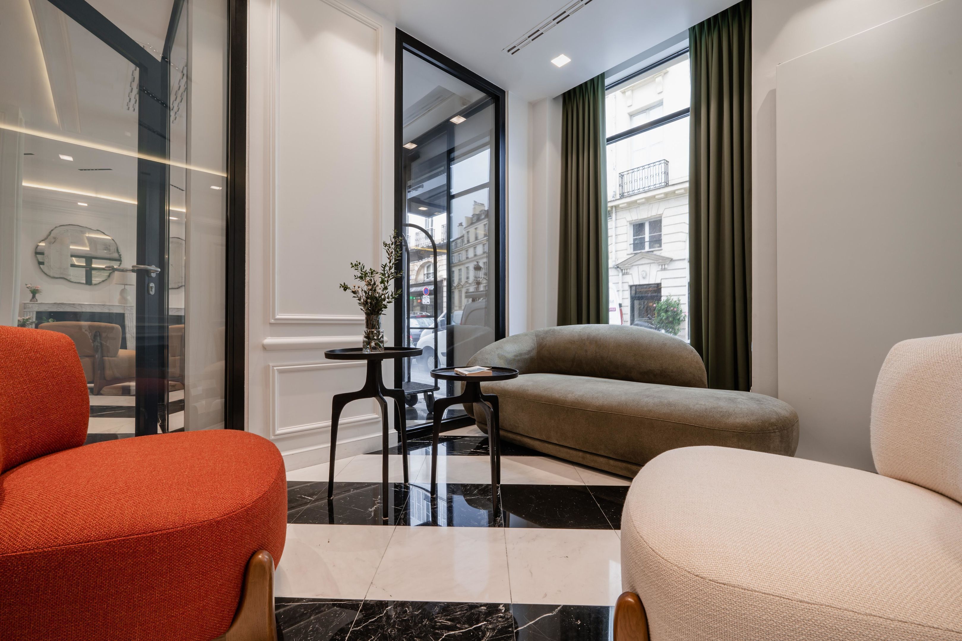Una habitación de hotel moderna con un ventanal grande, un sofá, una silla y una mesita.