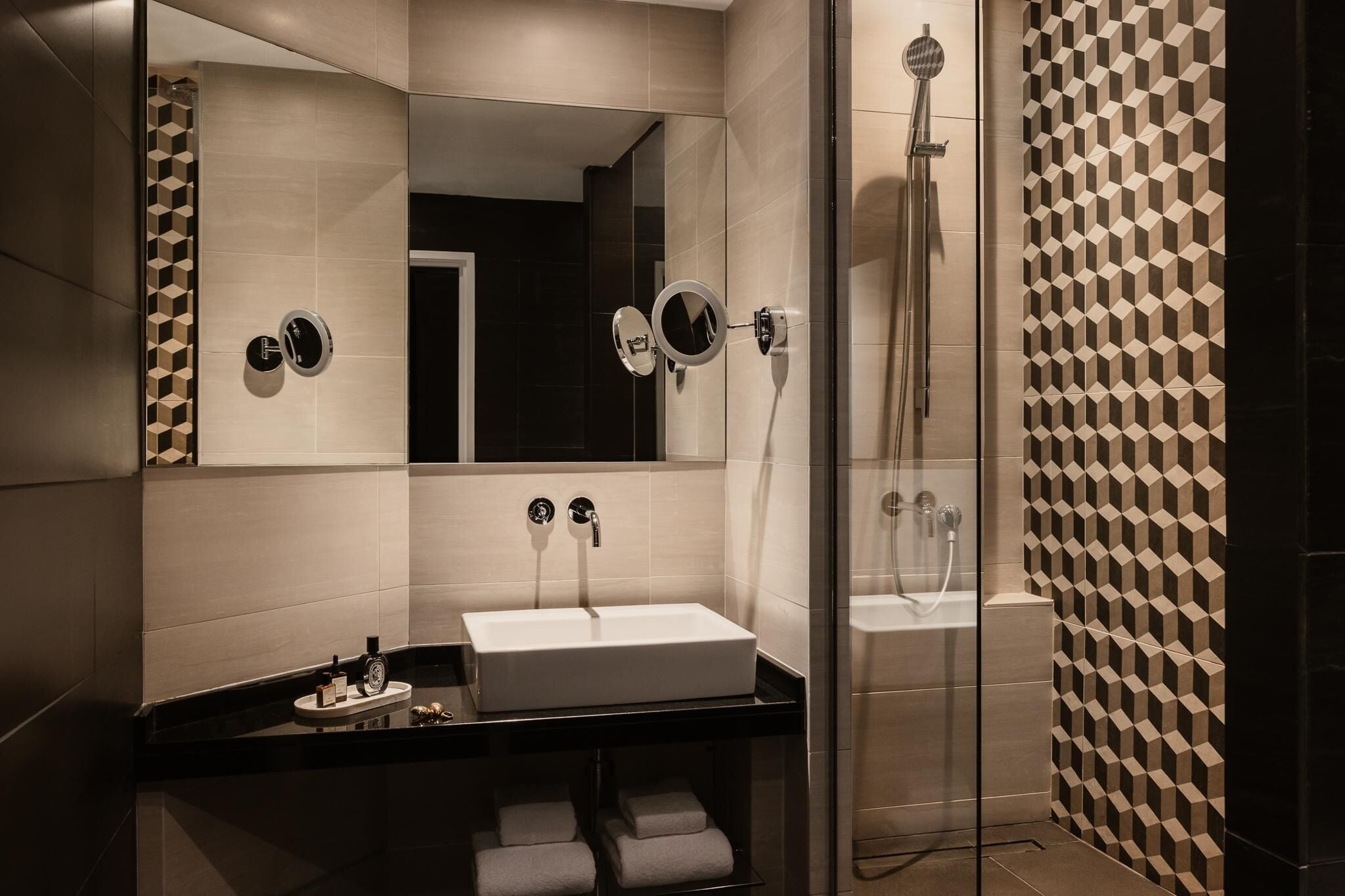 A modern bathroom with a large mirror, a sink, and a shower.