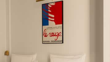 A hotel room with a bed, white bedding, and two brown pillows. A framed artwork hangs on the wall above the bed.