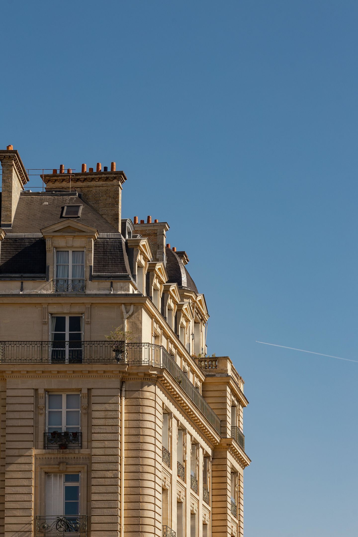 A multi-story building with a classic architectural style, featuring balconies and a clear sky.