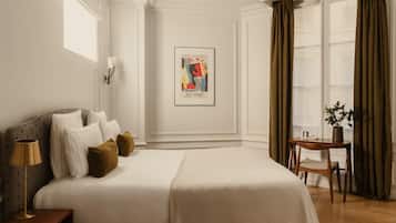 Une chambre d’hôtel avec un grand lit, une table de chevet avec une lampe, une affiche encadrée au mur et une fenêtre avec des rideaux.