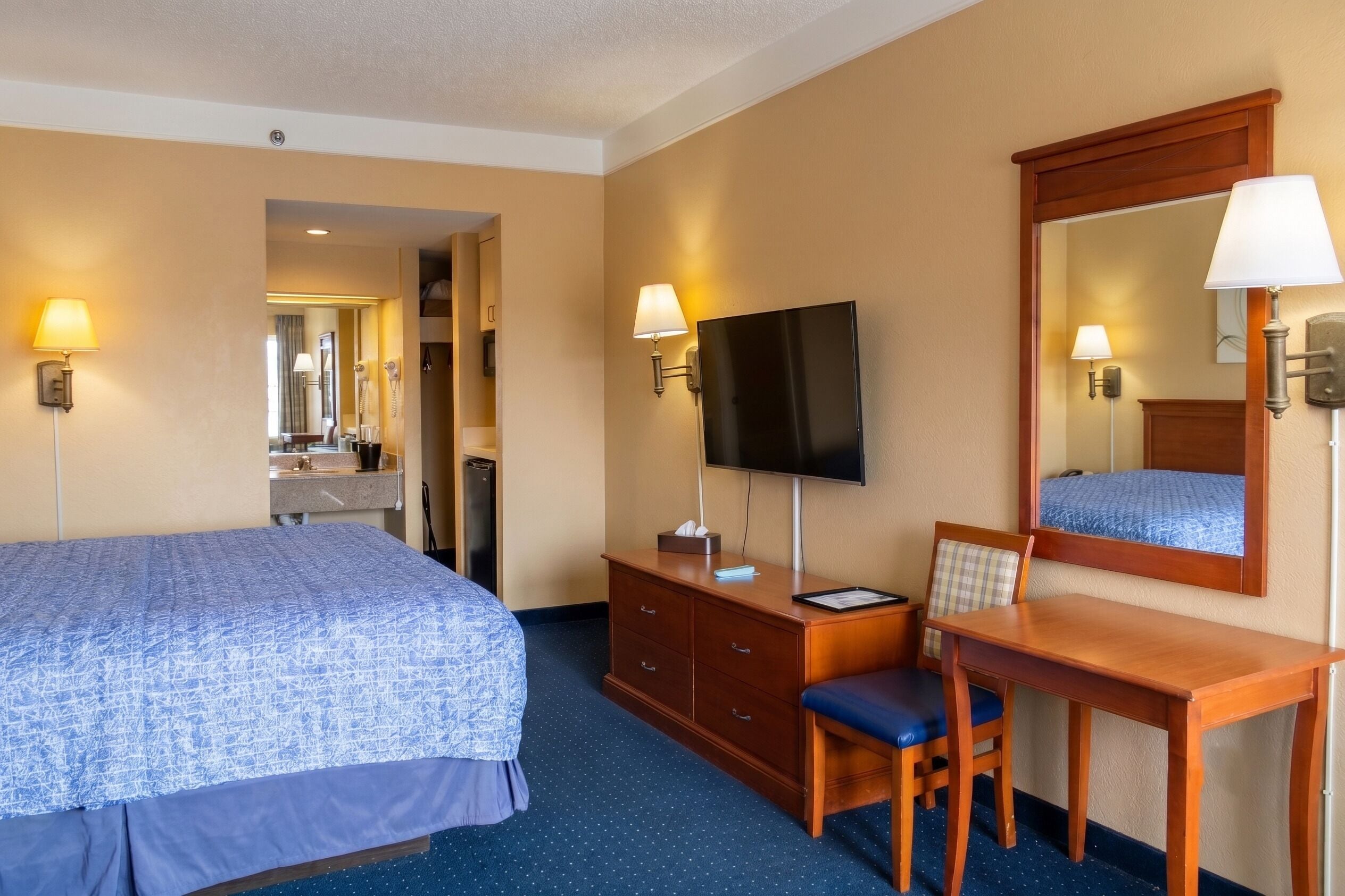 Une chambre d’hôtel comprenant un lit, un bureau, une chaise, une télévision et un miroir.