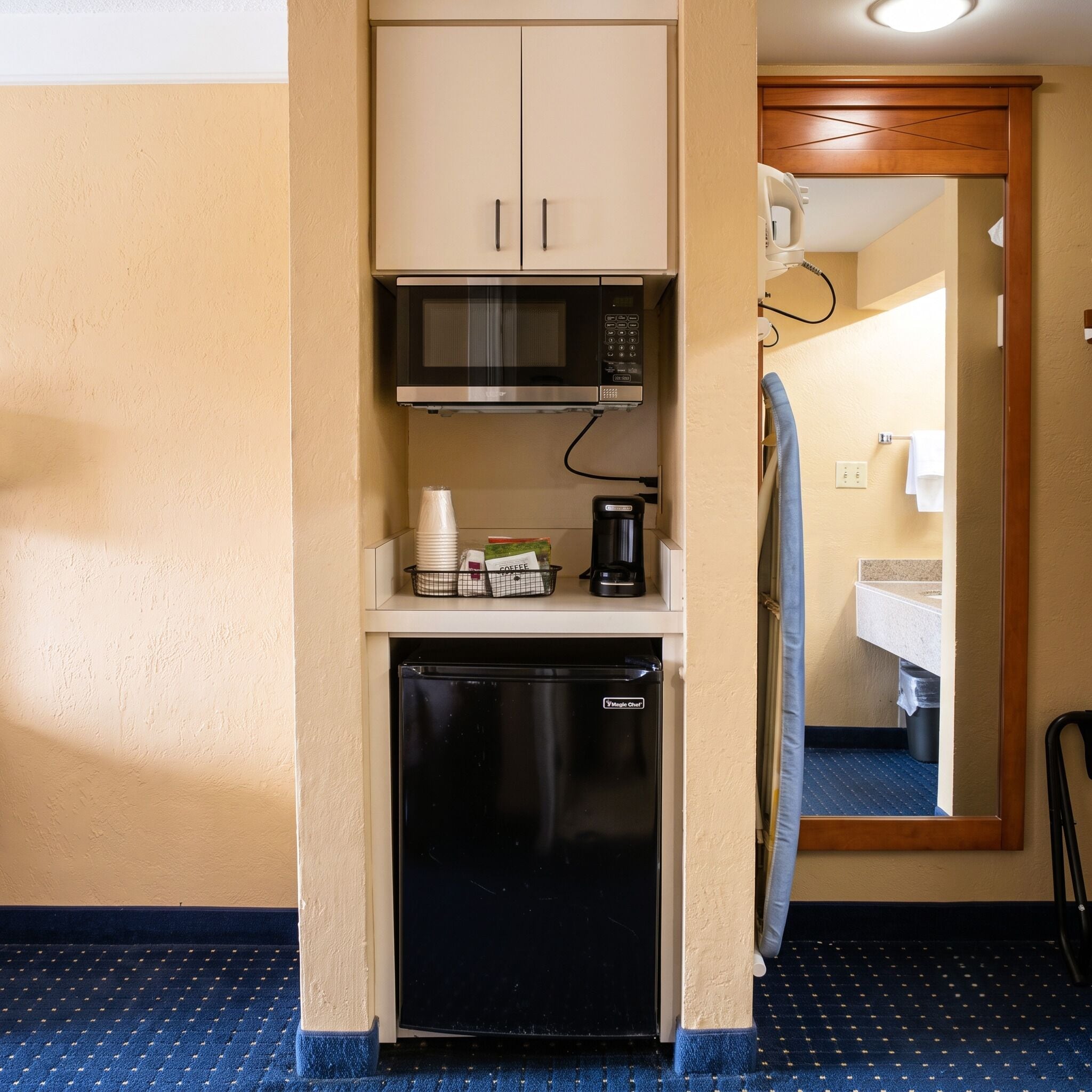 A compact kitchenette with a microwave, coffee maker, and a small refrigerator.