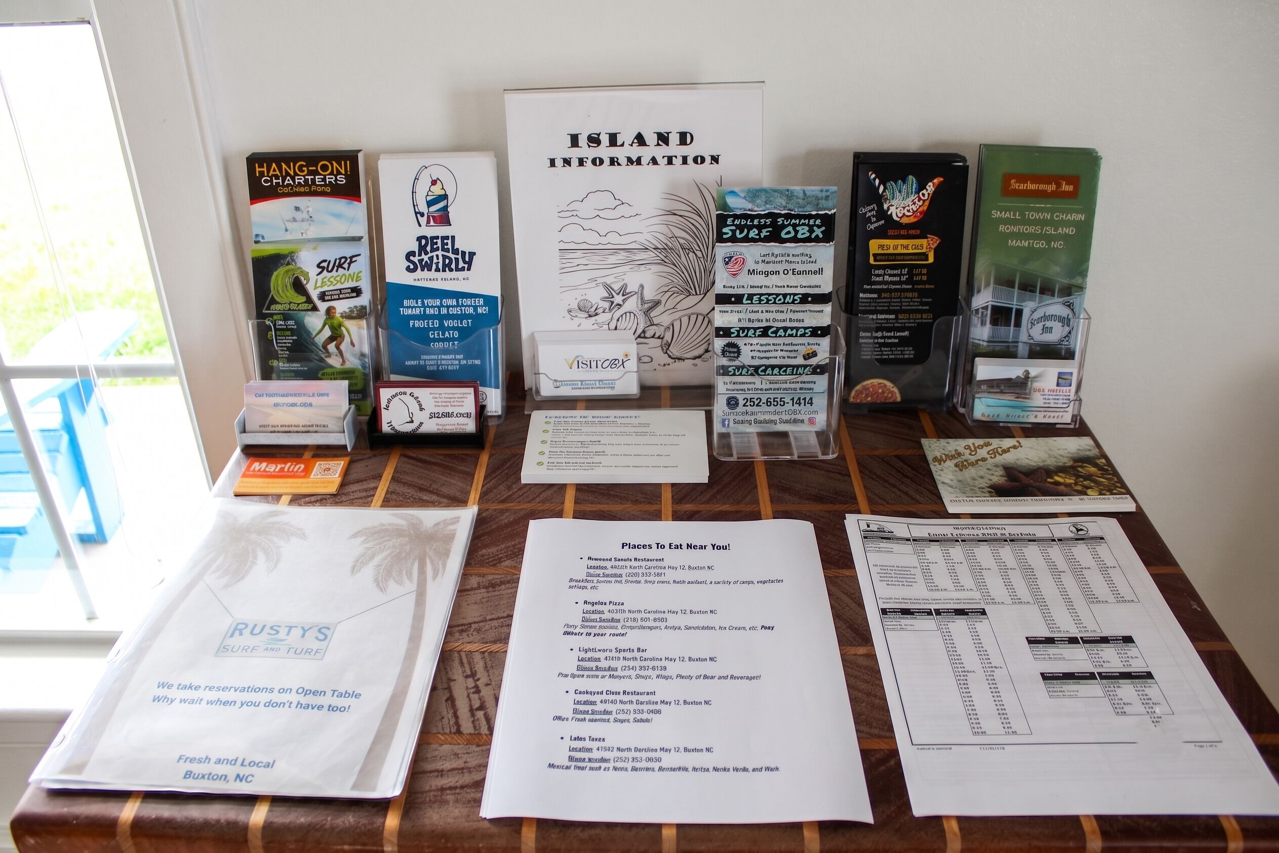 A table with various informational brochures and a menu for places to eat near the location.