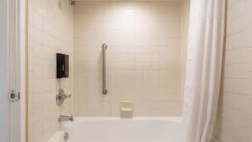 Een badkamer met een witte badkuip, een handdouche, een handgreep en een zeepdispenser.