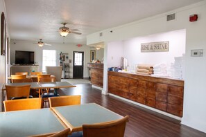 A dining area with tables and chairs, a television, and a counter with towels.