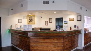 A reception desk with a wooden finish, a framed picture above it, and a sign indicating pet policies.