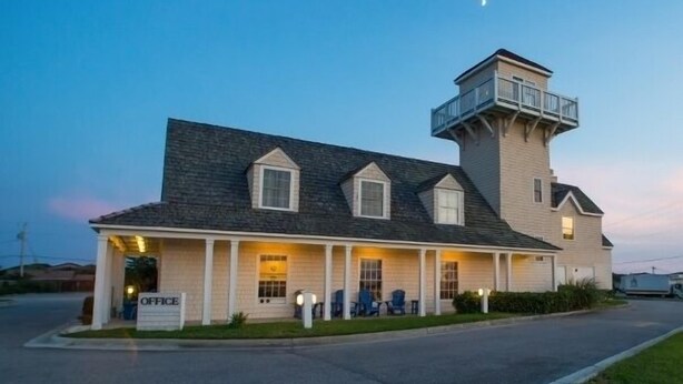 Kaksikerroksinen rakennus, jossa on huomattava torni ja katettu kuisti.