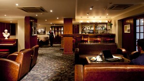 Eine Bar mit Ledersitzgelegenheiten, einem Klavier und einem Barkeeper.