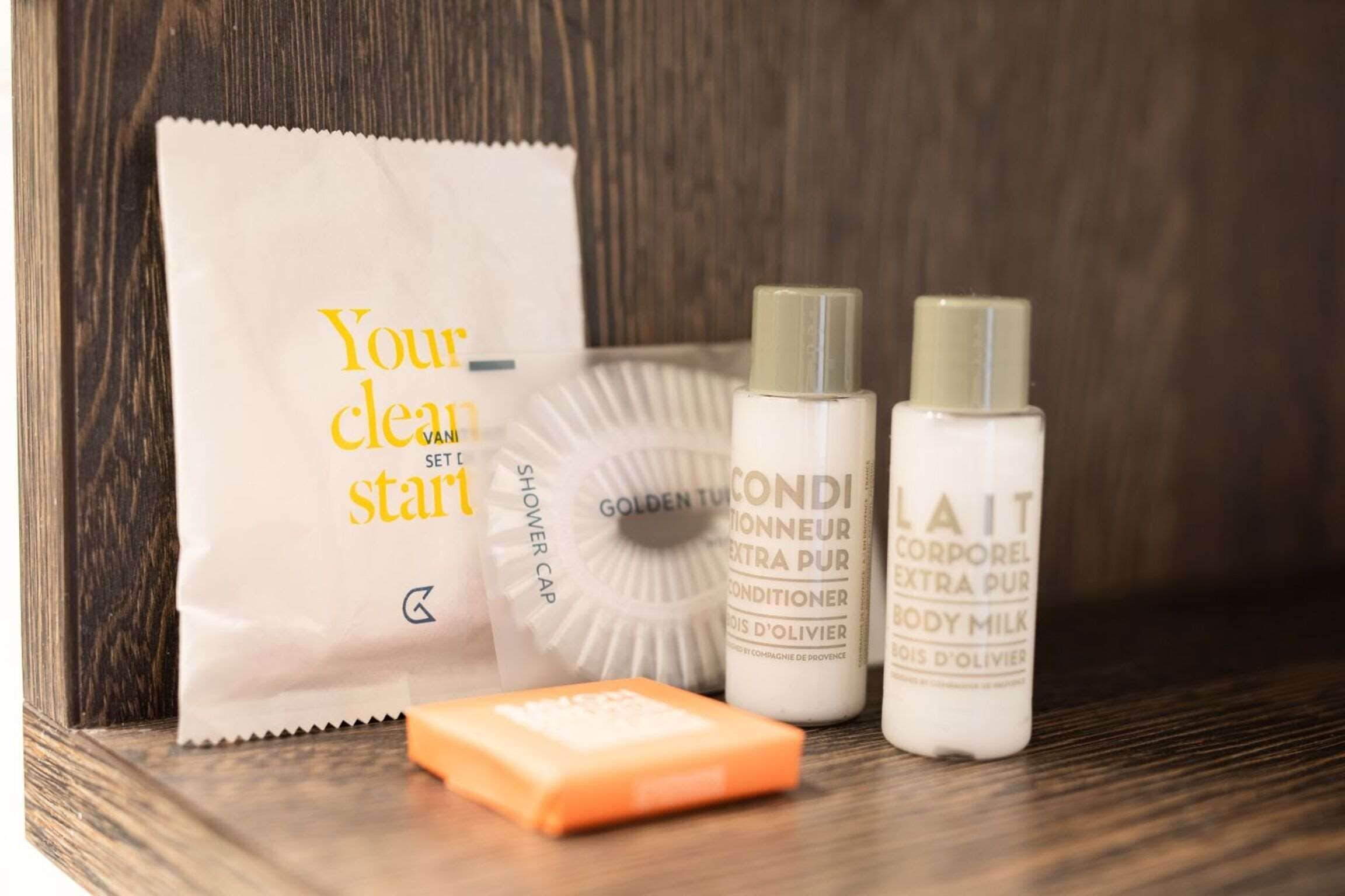 A set of toiletries including a shower cap, body milk, and a bar of soap.