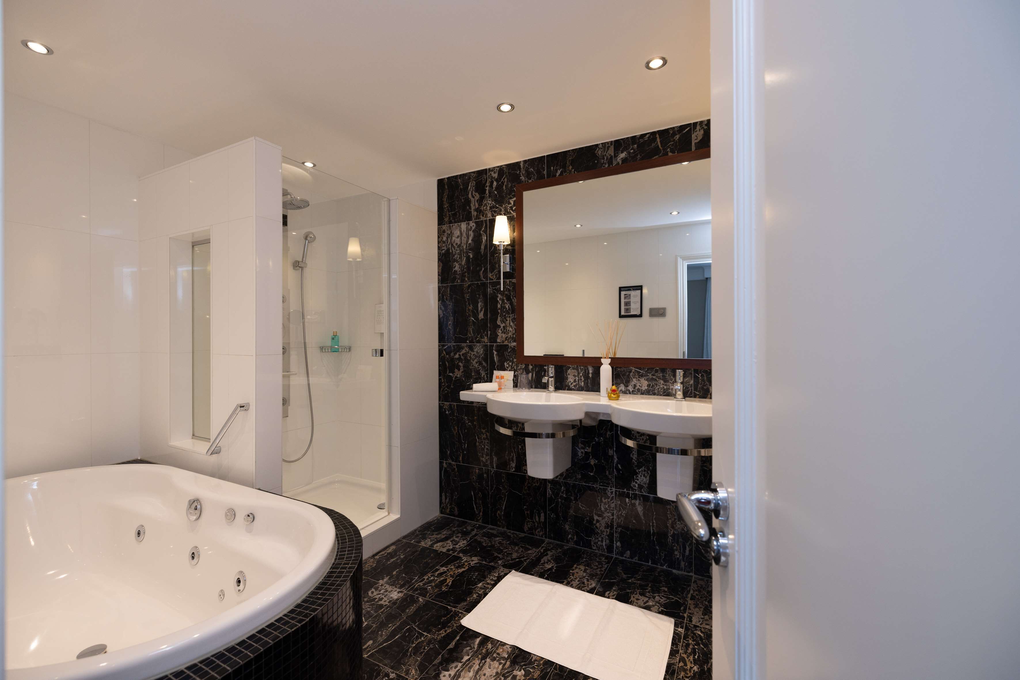 Un baño moderno con una bañera grande, una ducha a ras de suelo y dos lavamanos.