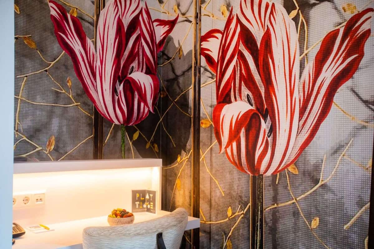 A room with a desk, a chair, and a wall with a floral mural.