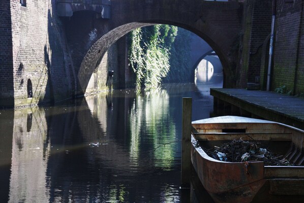 Un canal con un puente de ladrillo, un muelle de madera y un bote.