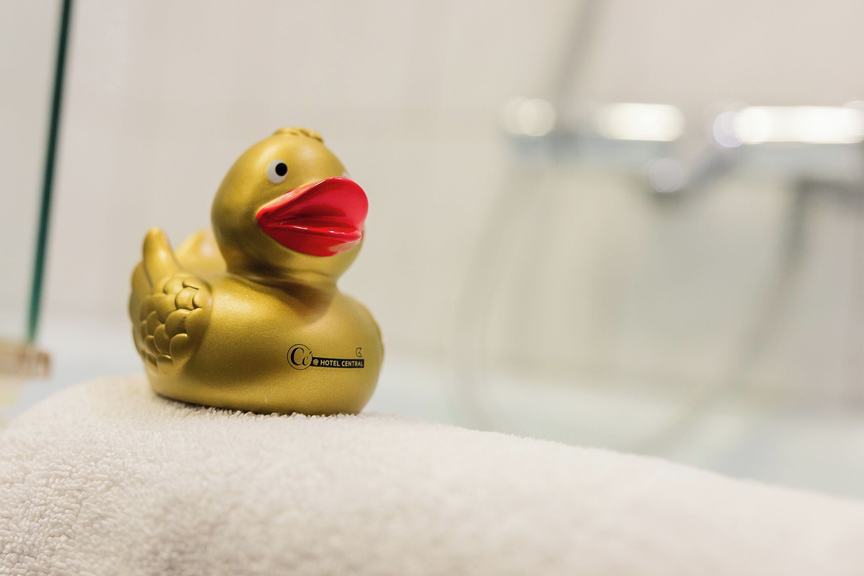 A golden duck-shaped object with a red beak and a logo on a white surface.