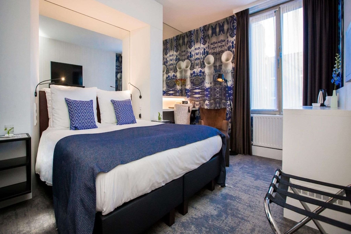 A modern hotel room with a large bed, a desk, and a chair.