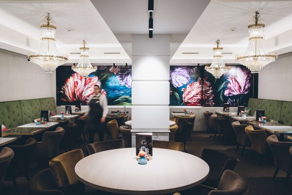 A restaurant with round tables, green upholstered booths, and chandeliers. - Golden Tulip Hotel Central ('s-Hertogenbosch)