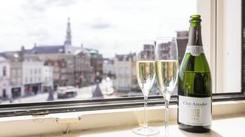 Uma garrafa de vinho Clos Amador Brut Delicat e duas taças em um parapeito com vista para a cidade.