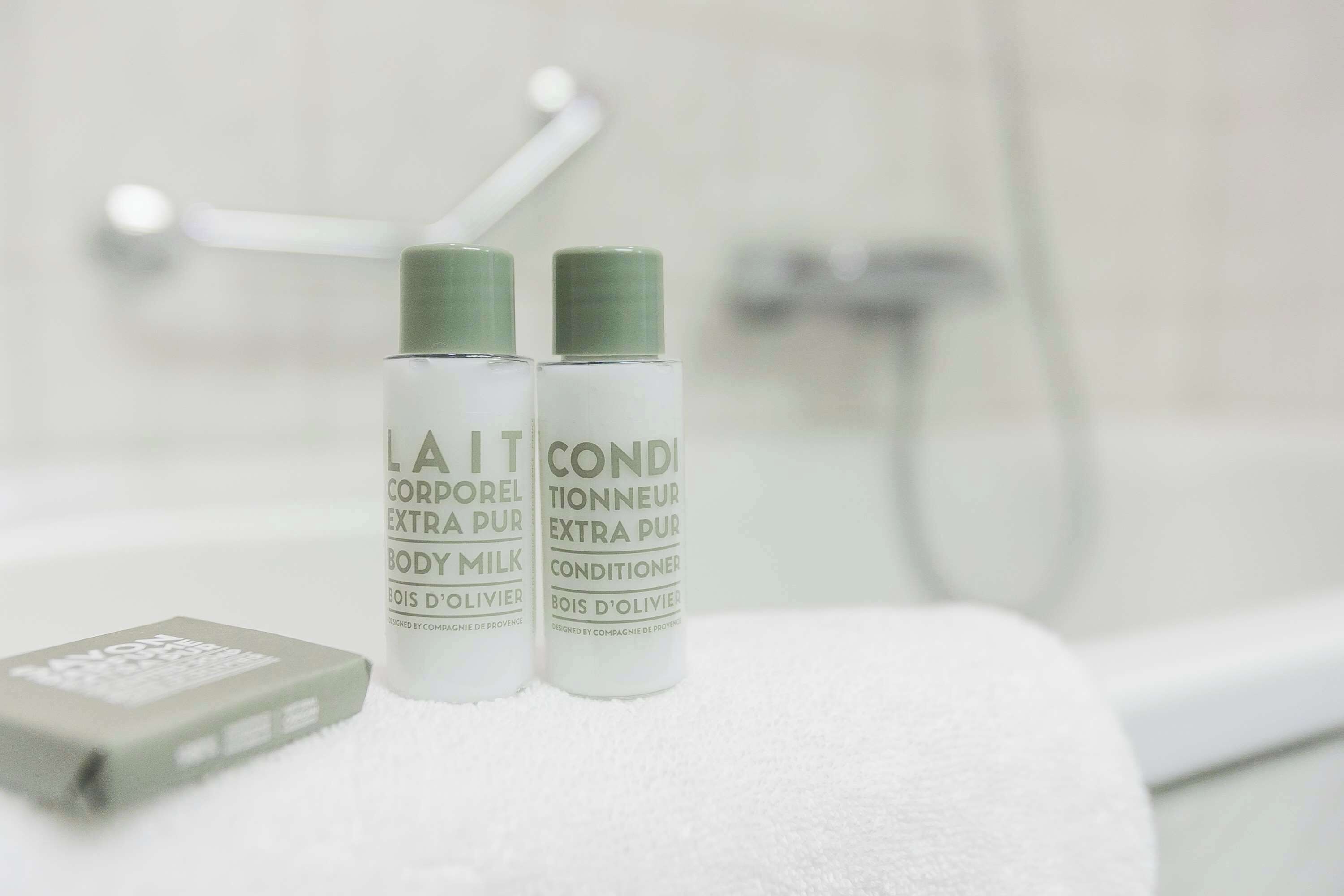 Two bottles of body milk and conditioner on a white towel.