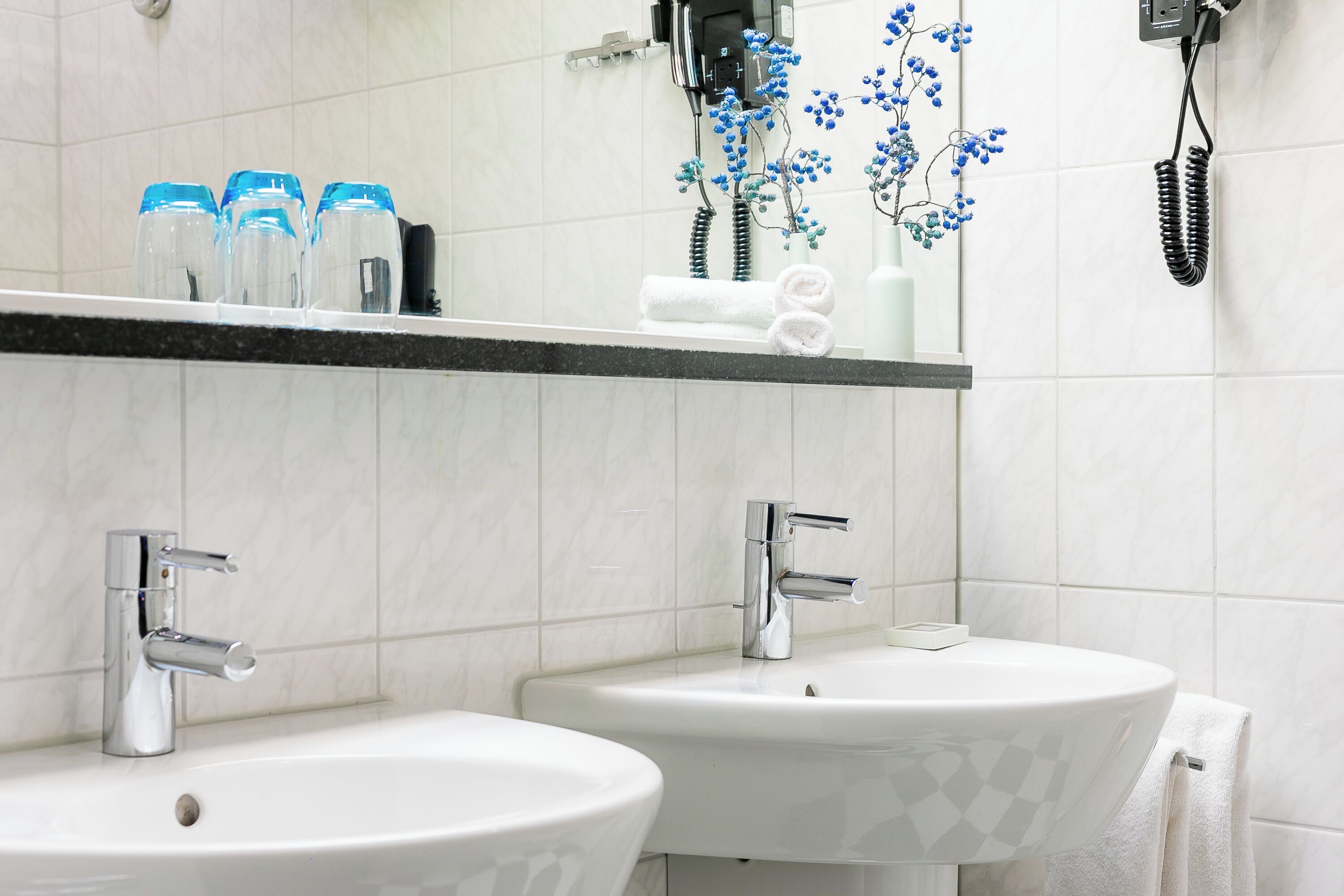 A bathroom with two sinks, a mirror, and a shelf with toiletries.