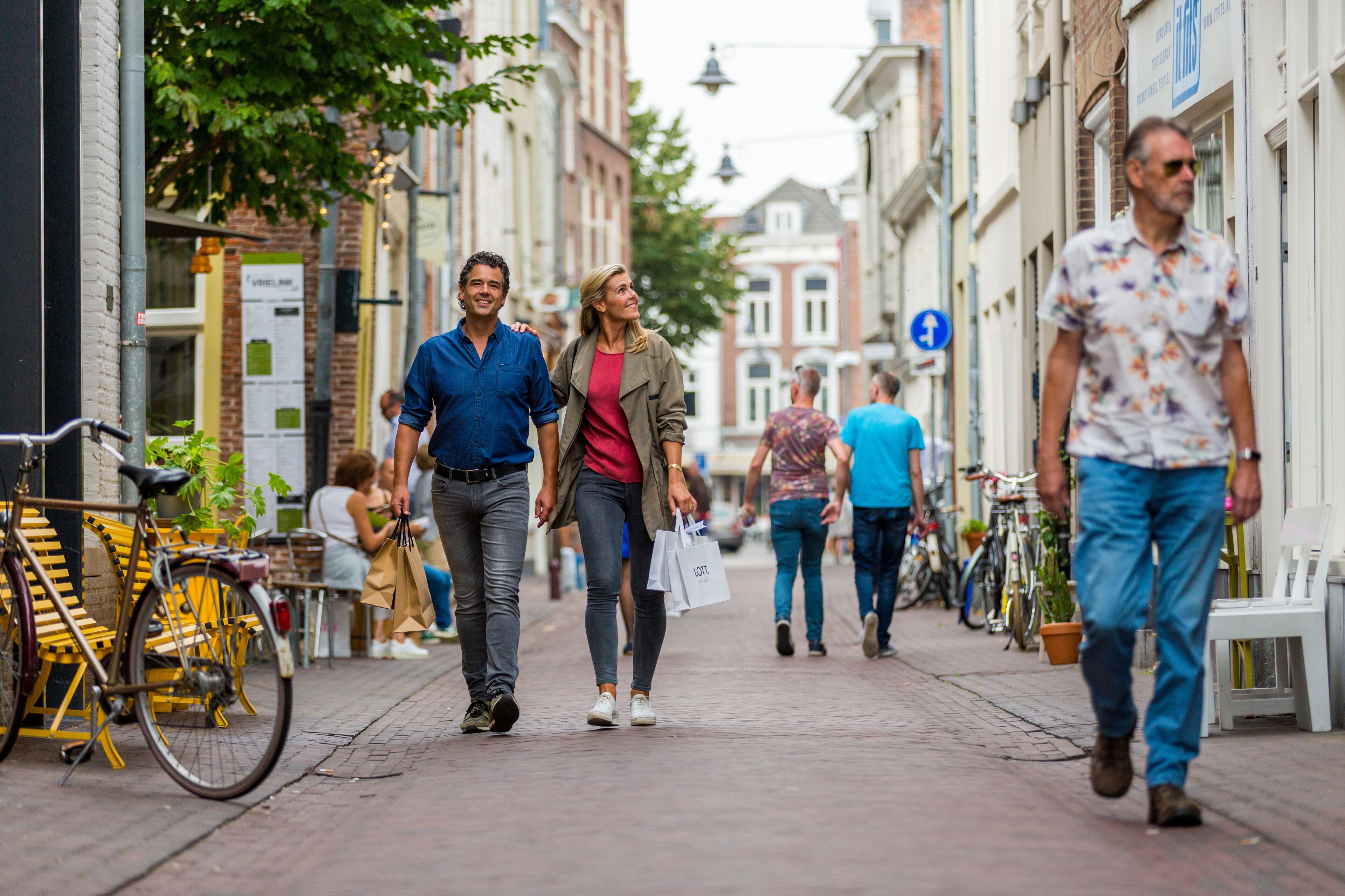 A pedestrian street with buildings, bicycles, and people walking.