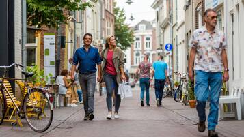 A pedestrian street with buildings, bicycles, and people walking.