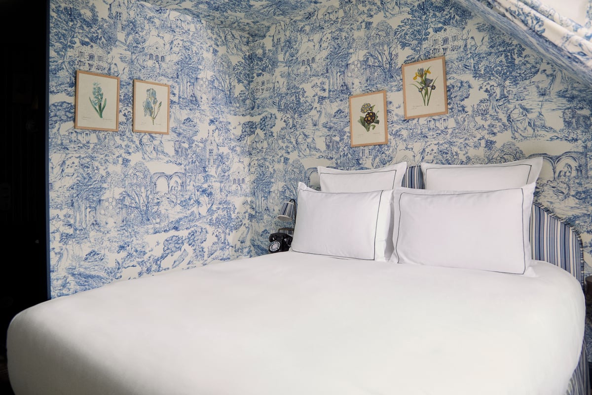 Relax in a serene bedroom with a large bed, white linens, and botanical prints.