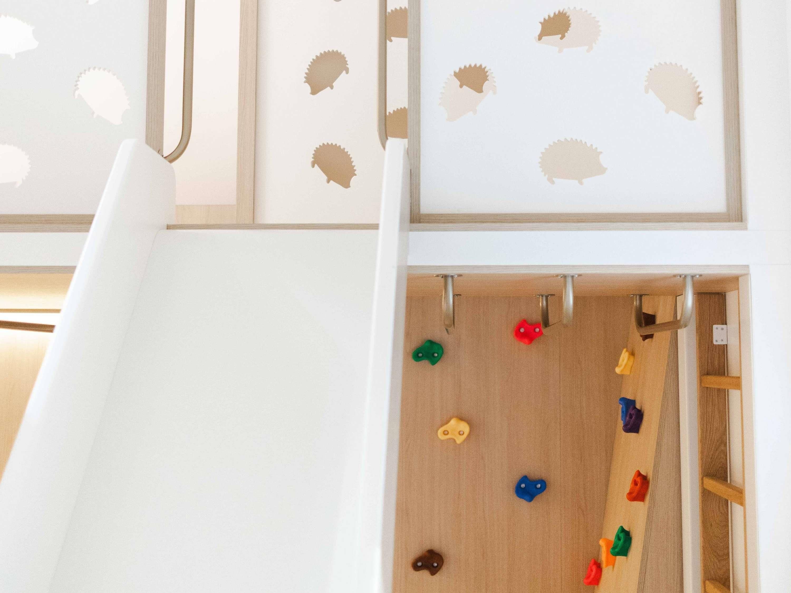Zona de juegos infantiles con un tobogán y una pared de escalar.
