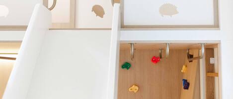 Zona de juegos infantiles con un tobogán y una pared de escalar.