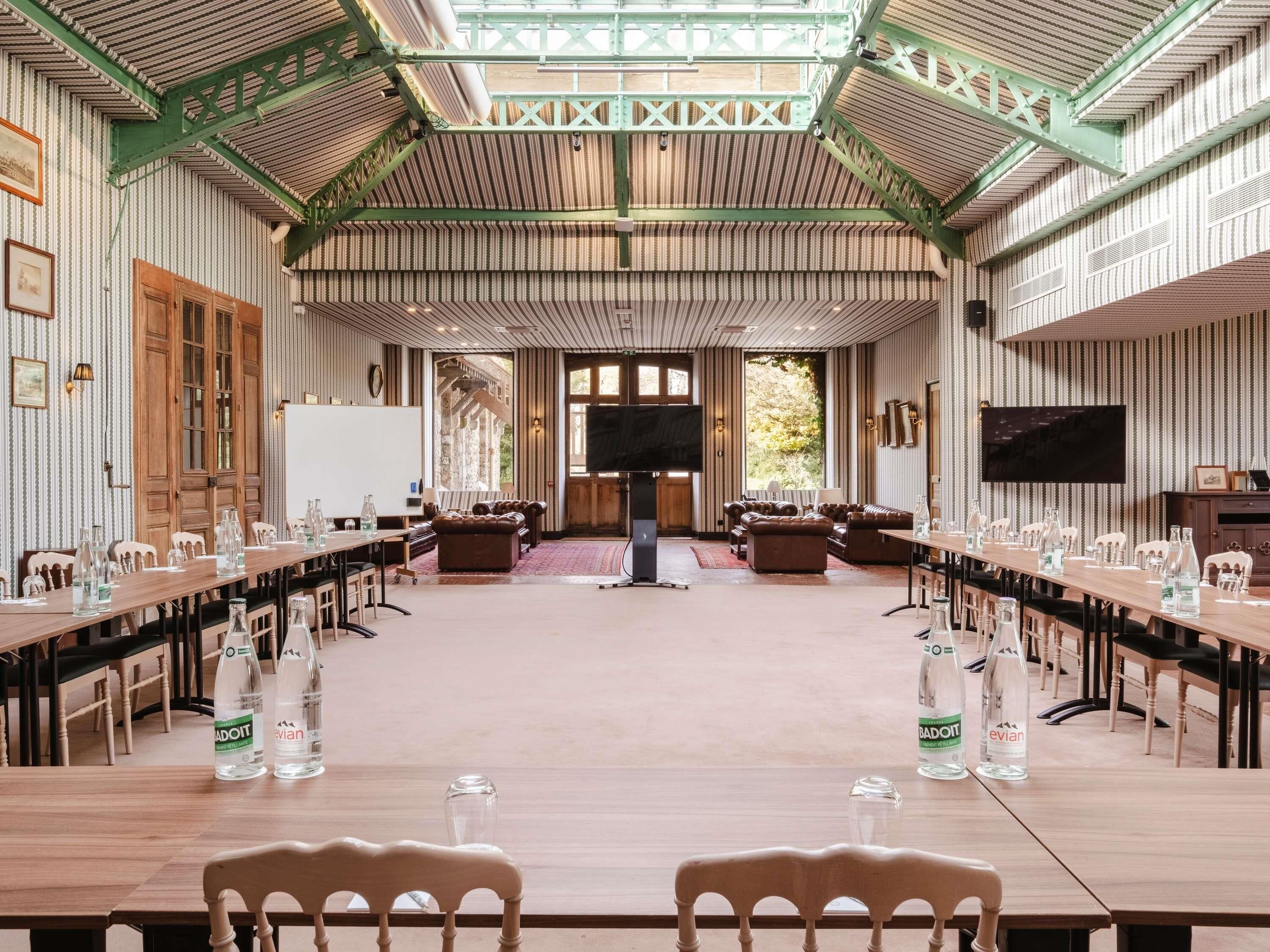 A conference room with a long table, chairs, and a television screen.