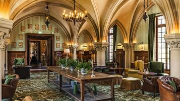 A grand lobby with high arched ceilings, a large wooden table, and comfortable seating.