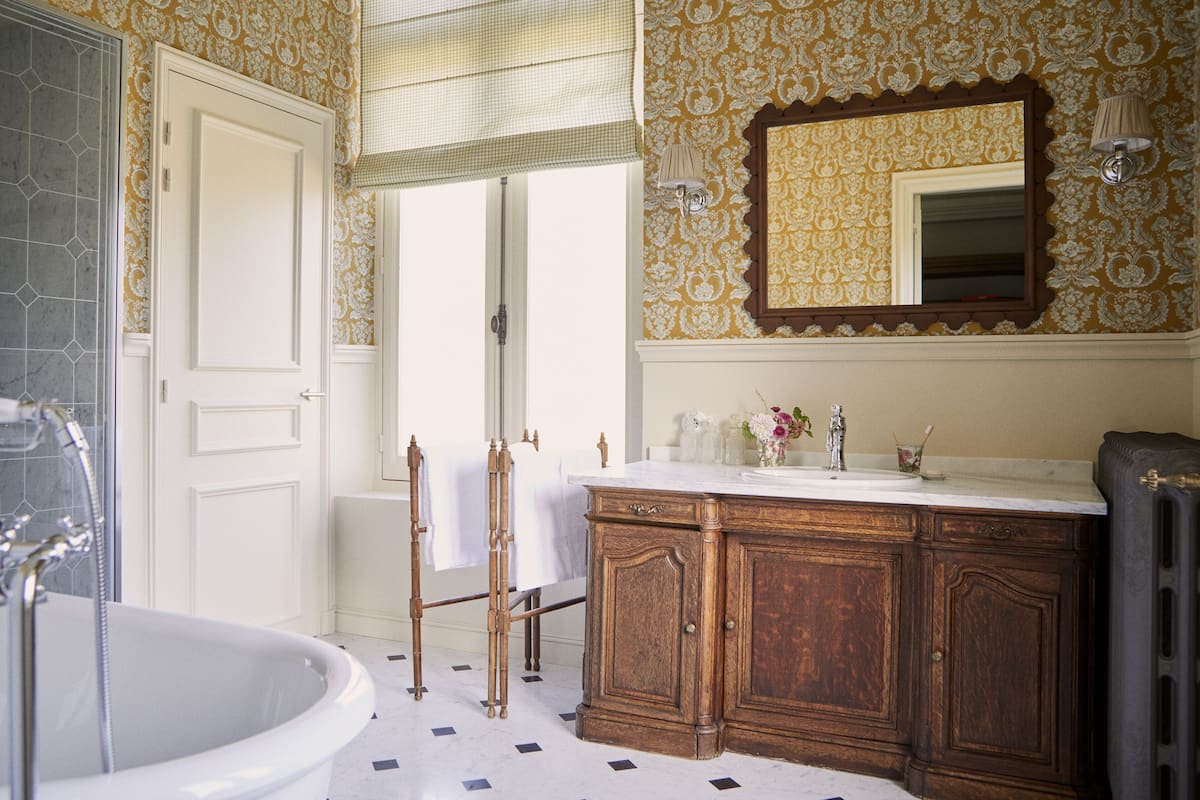 Bathroom features a bathtub, wooden vanity, and a geometric tile floor.