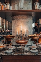 Disposição de buffet com vários recipientes de servir e um arranjo de velas.