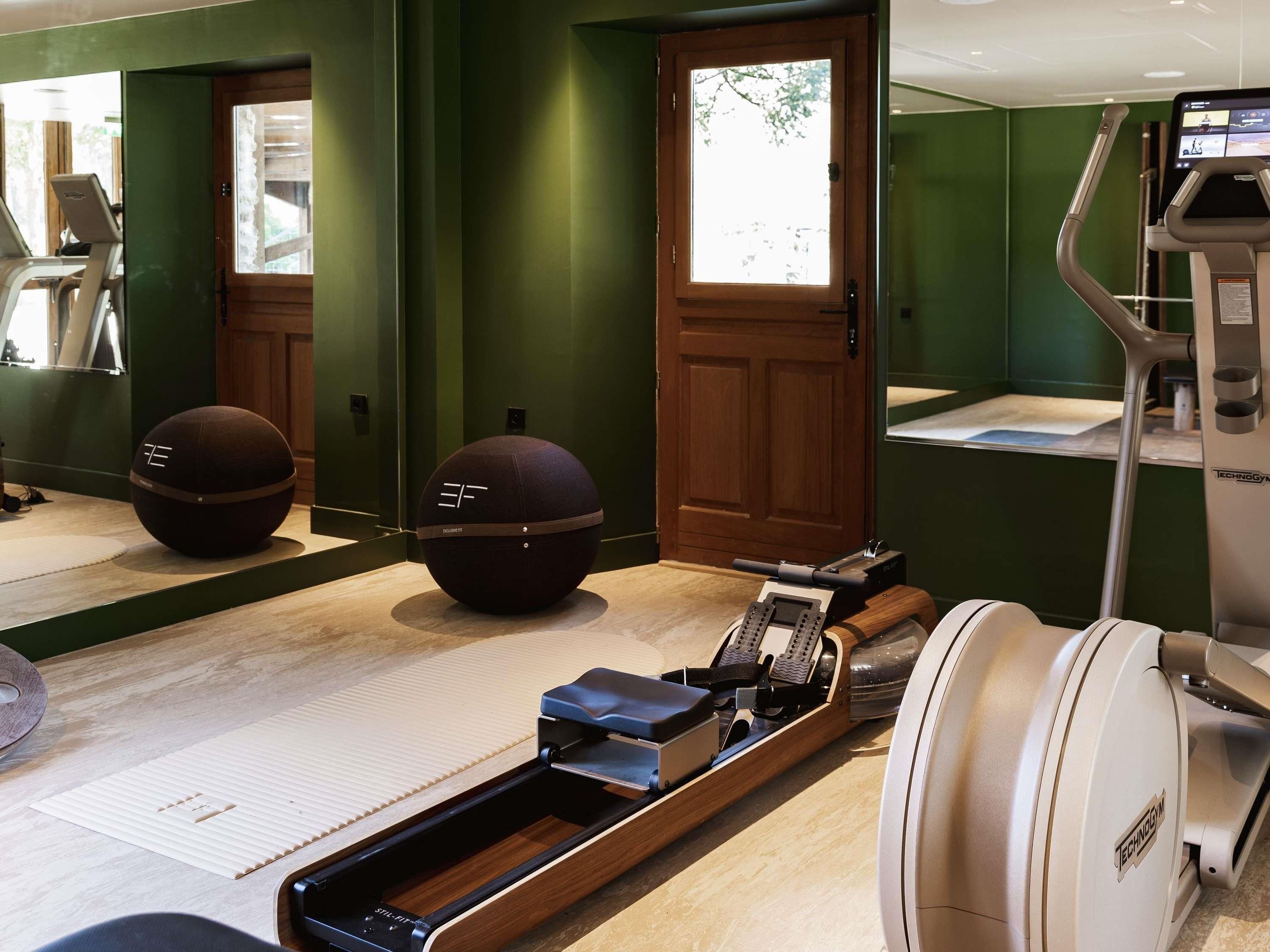 Ein Fitnessraum mit Trainingsgeräten, einer Tatami-Matte und einer Holztür.