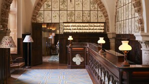 An arched hallway with a patterned carpet, wooden furniture, and a chandelier. - Abbaye des Vaux De Cernay, a Paris Society Collection hotel (Cernay-la-Ville)