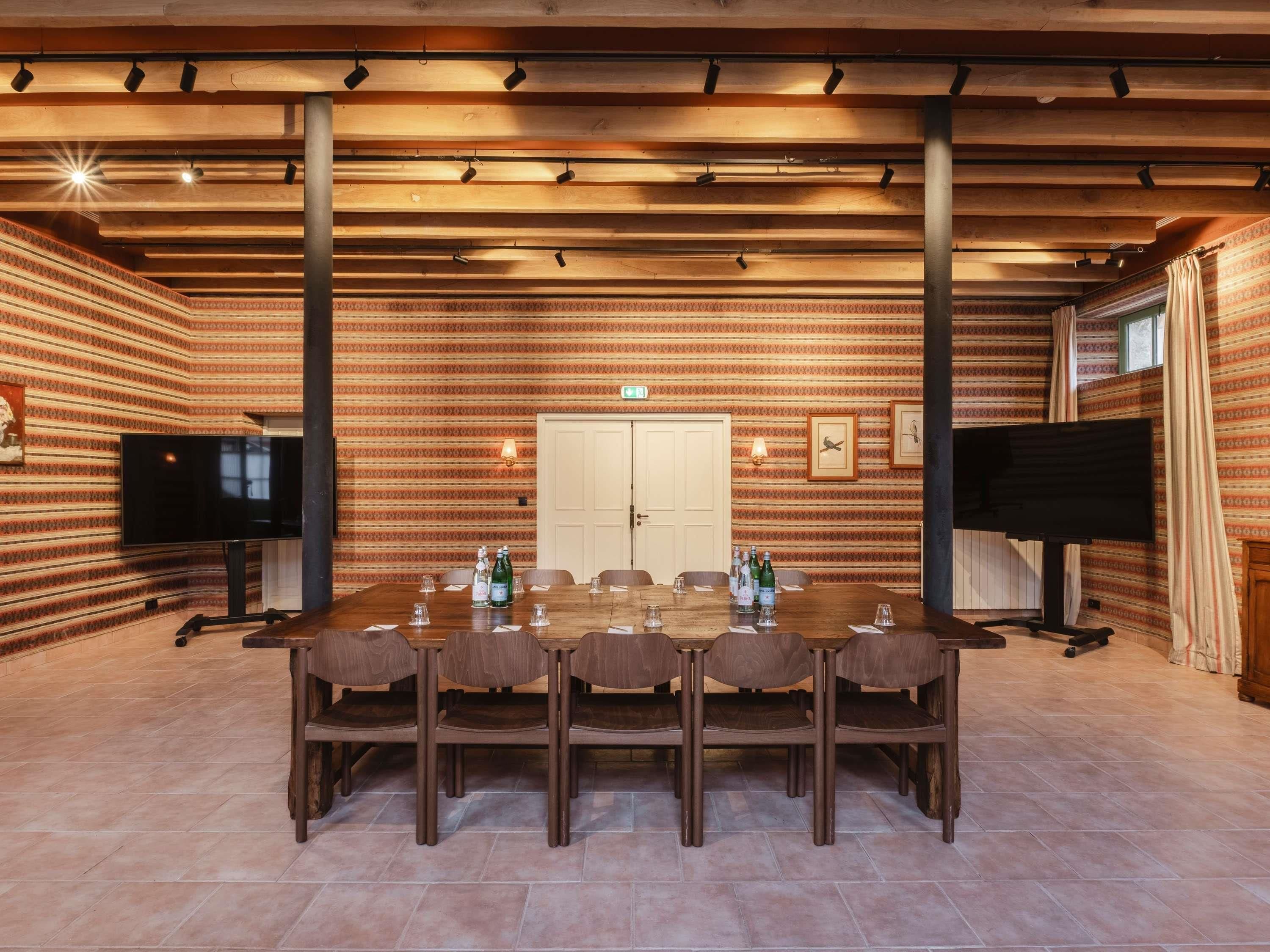 A conference room with a long table, chairs, a television, and a piano.